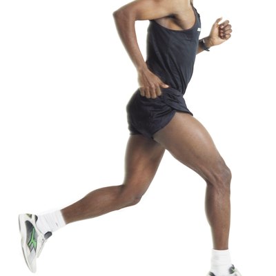 a male african american runner wearing black shorts and shirt is running in profile to the camera