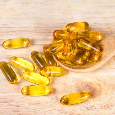 Closeup yellow soft gelatin supplement fish oil capsule on woode