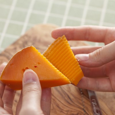 Hands pulling apart two pieces of cheese