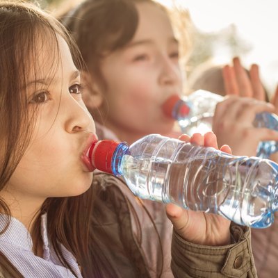 Photo of two girls drinking water from PET bottle