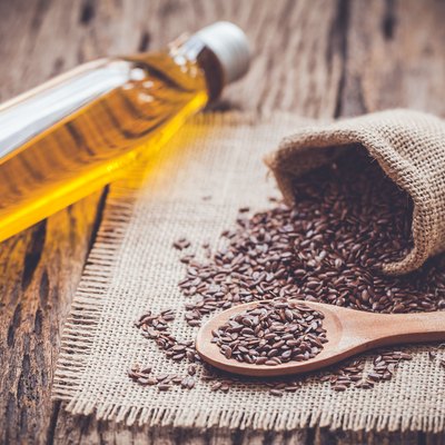 Flax seeds in the sack and oli on wooden background