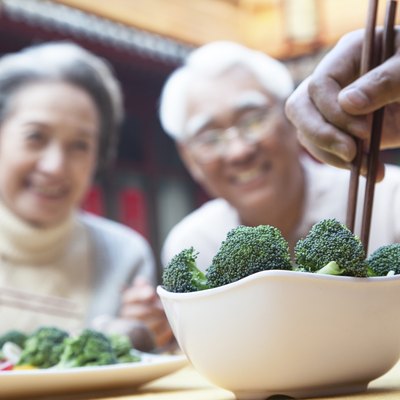 Hand picking up broccoli with chopsticks
