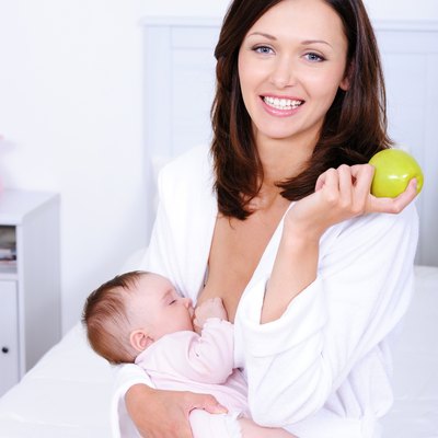 Woman with green apple breastfeeding her baby