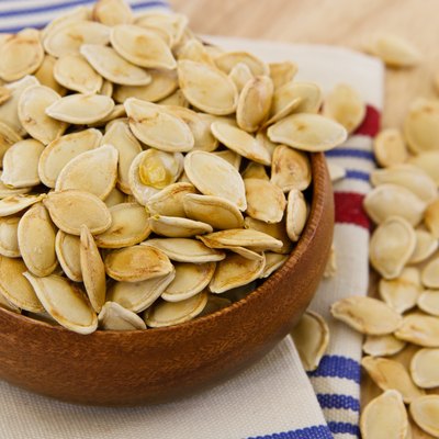 Toasted pumpkin seeds overflowing a wooden bowl