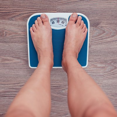 Girl is measuring her weight on the scales.