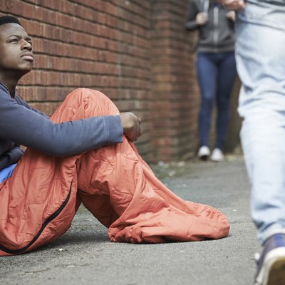 Homeless Teenage Boy In Sleeping Bag On The Street