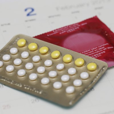 birth control pills with condom on a calendar