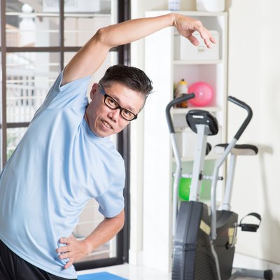 Mature Asian man arms stretching at gym