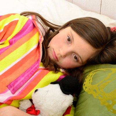 little girl in her bed has a stomachache