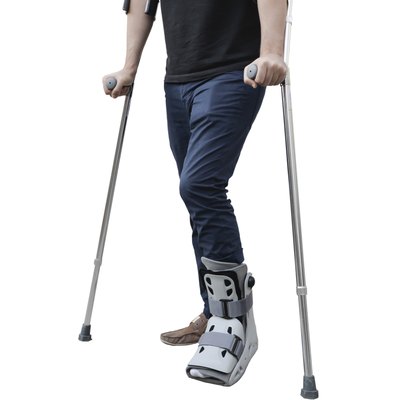 broken leg man wearing ankle support with walking crutches