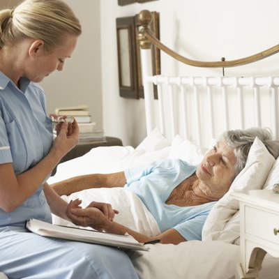 Nurse Taking Pulse Of Senior Patient In Bed