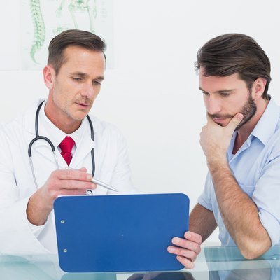 Male doctor discussing reports with patient at desk