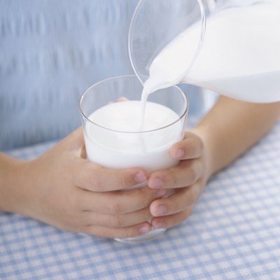 A child's hands holding a glass of milk