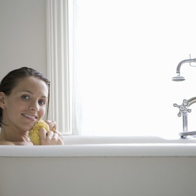 Young woman with sponge in bath, smiling, portrait