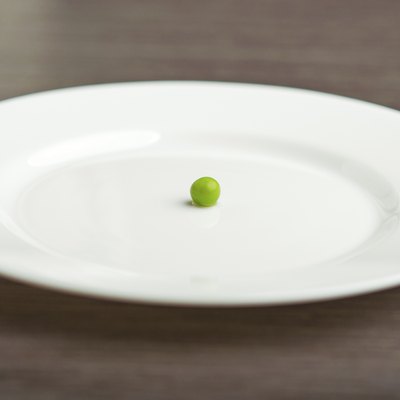 diet concept. one pea on an empty white plate