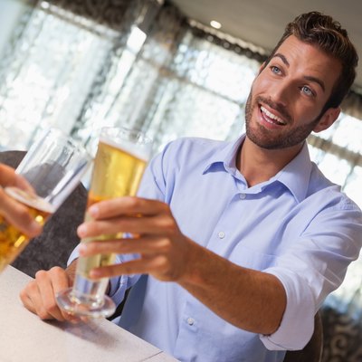 Smiling businessman clinking glass of beer with bartender