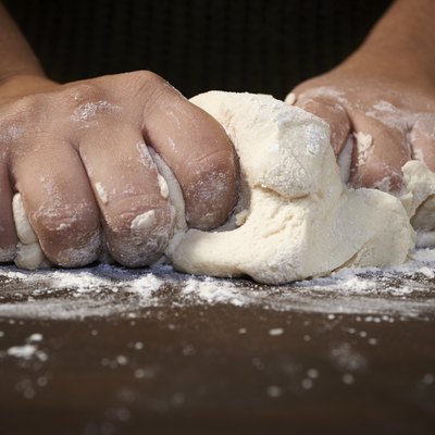 woman's hands kneading dough on wooden table