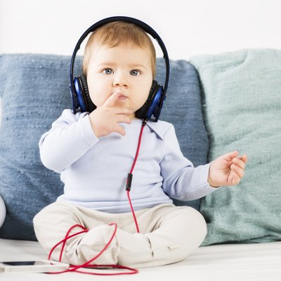 Adorable baby boy listening music at earphones.