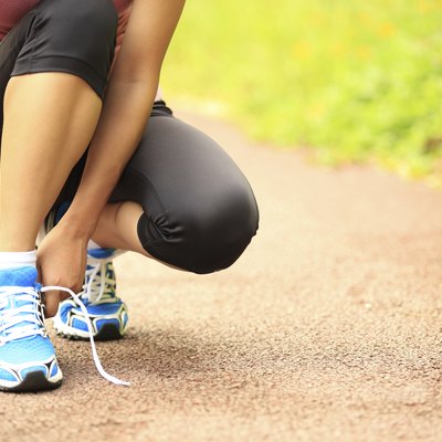 woman runner tying shoelaces on trail