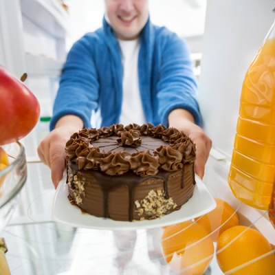 Boy take chocolate cake from fridge