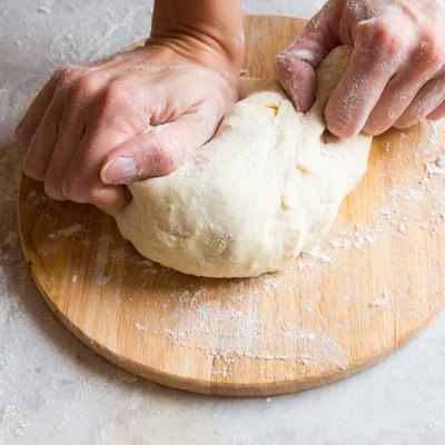 Hands knead dough