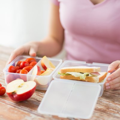close up of woman with food in plastic container