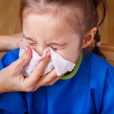 Parent hand helping little girl to blow her nose