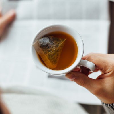 Man holding cup of tea and reading the newspapers