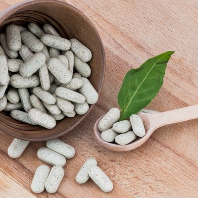Alternative pills on a wooden spoon and in a bowl