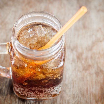 Glass of cola with ice on wooden table