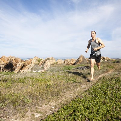 Male athlete running barefoot and fast on a walking trail