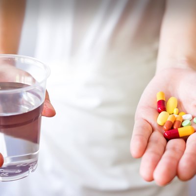 Hands with pills and glass of water isolated on white