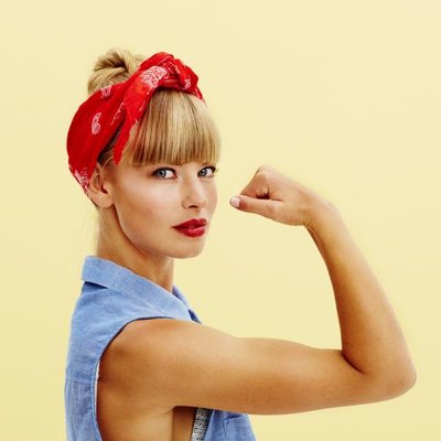 Strong young blond woman flexing muscle, portrait