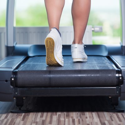 Fitness girl running on treadmill. Woman with muscular legs in