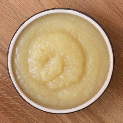 Apple sauce in rustic brown dish on dark wood.