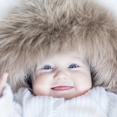 Funny baby girl with blue eyes wearing huge winter hat