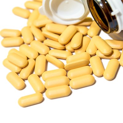 Piles of vitamin tablets drop from brown bottle isolated