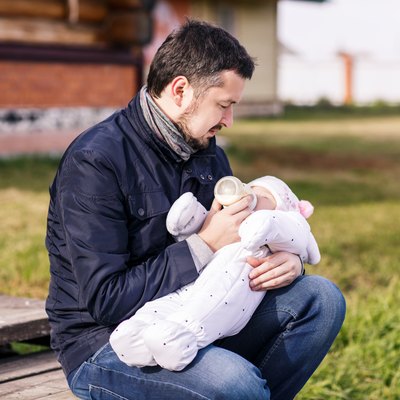 Portrait of father feeding newborn baby