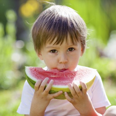 Boy, eating watermelon in the garden, summertime