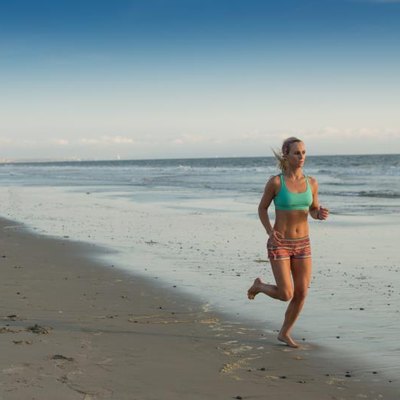 Young woman runs on beach at sunset
