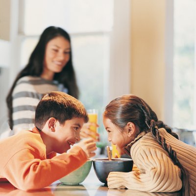 Brother and Sister Eating Breakfast in a Kitchen, Mother in the Background