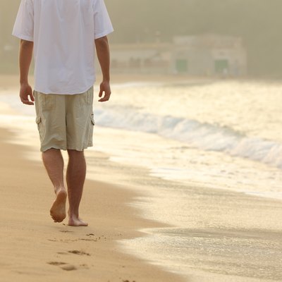 Man walking and leaving footprints on the sand of beach