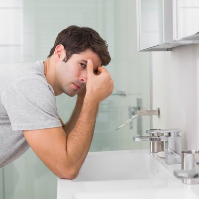 Tensed young man at washbasin in bathroom
