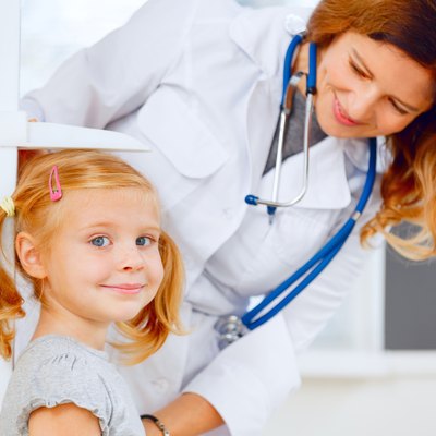 Doctor measuring height of a cute redhead girl.