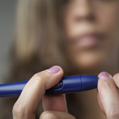 Close-up of a young woman taking a blood sample from her finger with a glaucometer