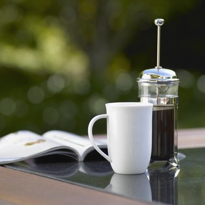 Coffee cup and plunger with magazine on table