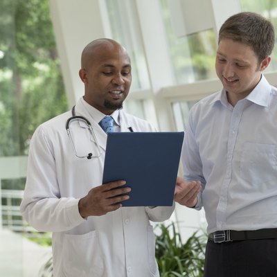 Doctor and patient looking down and discussing medical record in the hospital