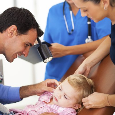 pediatrician examining little girl's ear
