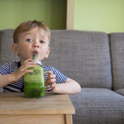 cute child drinking a green smoothie