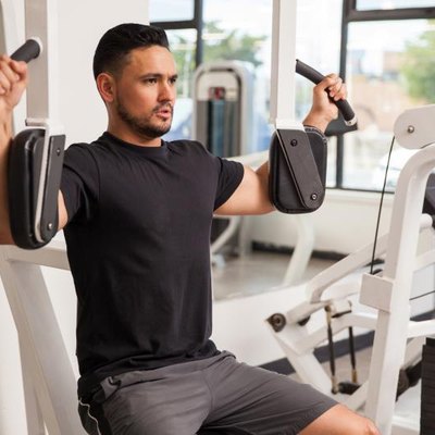 Good looking young man building muscle at the gym using a pec deck machine
